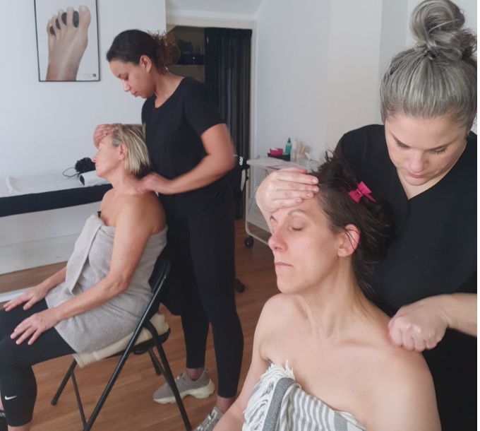 Students practising Indian head massage in a training room
