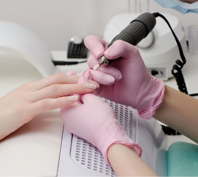 Nail technician using an electric e-file on a client's nails