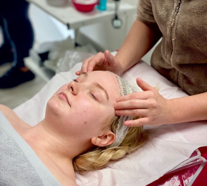 Student giving a facial massage in a training room