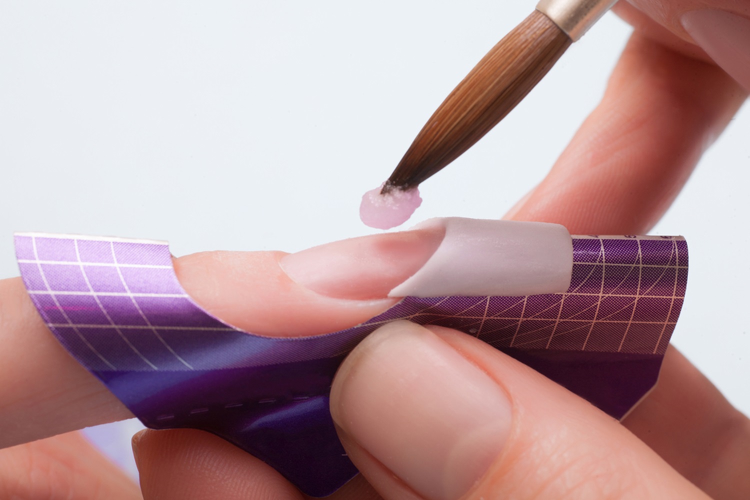 Pink and white acrylic being sculpted on a nail form