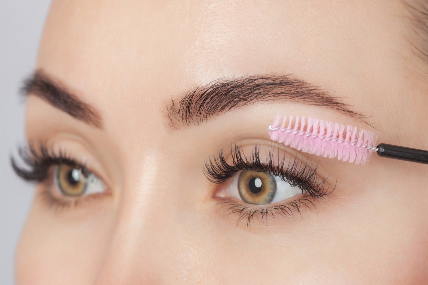 Mascara wand brushing through long lashes